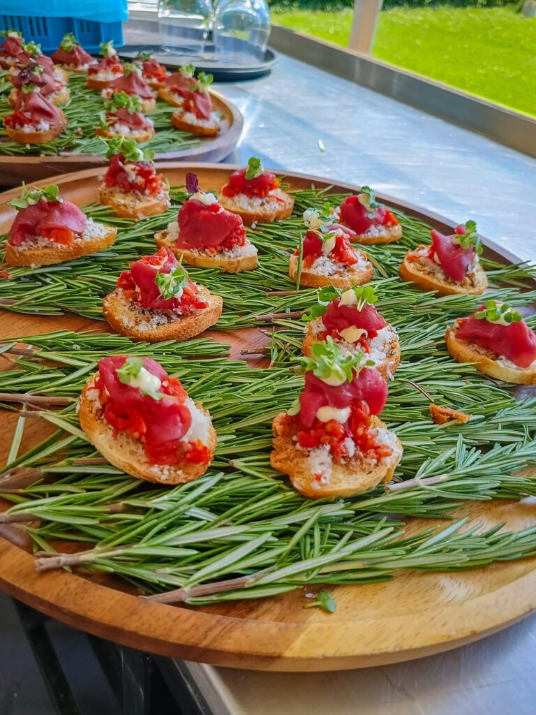 Bruschetta hapjes met tomaat en kruiden op houten serveerplank met rozemarijn bij Feestlocatie Alegria